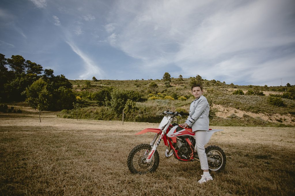 Plano general de Isidoro posando con su moto en el campo en la sesión de comunión en Ujué